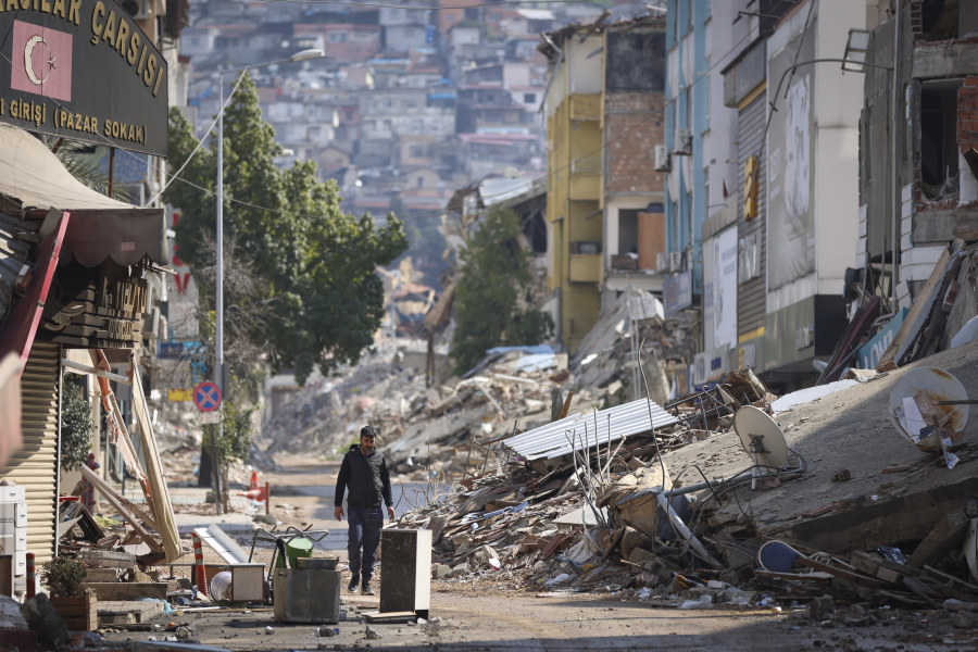 A man walks past destroyed buildings in Antakya, southeastern Turkey, Tuesday, Feb. 21, 2023. The death toll in Turkey and Syria rose to eight in a new and powerful earthquake that struck two weeks after a devastating temblor killed nearly 45,000 people, authorities and media said Tuesday.