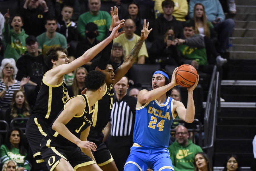 UCLA guard Jaime Jaquez Jr. (24) looks to pass the ball as Oregon's Nate Bittle (32), left, Kel'el Ware, middle front, and guard Rivaldo Soares, middle rear, defend during the first half of an NCAA college basketball game Saturday, Feb. 11, 2023, in Eugene, Ore.