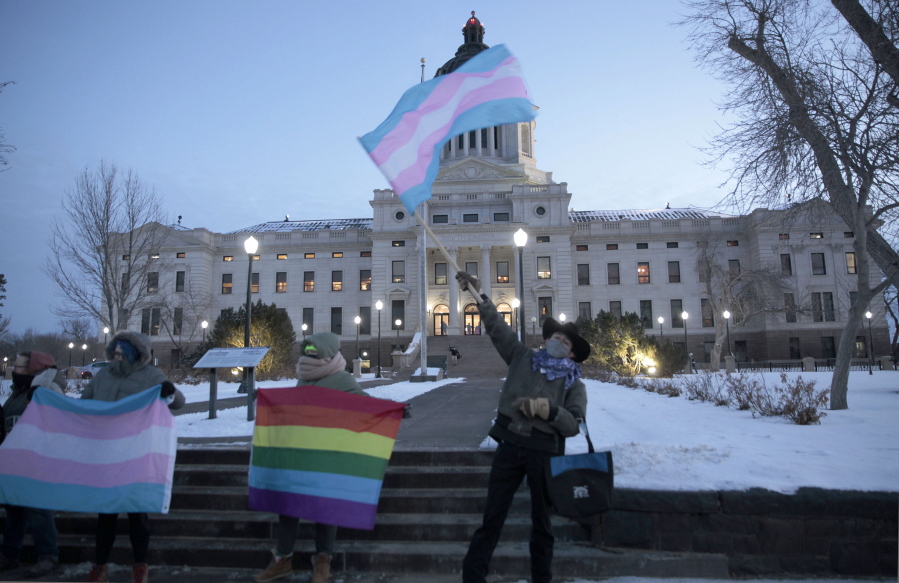 FILE - A group of LGBTQ advocates gathere outside the South Dakota Capitol in Pierre on Jan. 26, 2021, to protest a bill that would have banned people from updating the sex on their birth certificates. A Little Rock pharmacist's testimony before a legislative committee about gender affirming care for minors resulted in an Arkansas lawmaker asking about her genitalia. The exchange highlights the type of hostile rhetoric that transgender people say they're facing at statehouses across the country.
