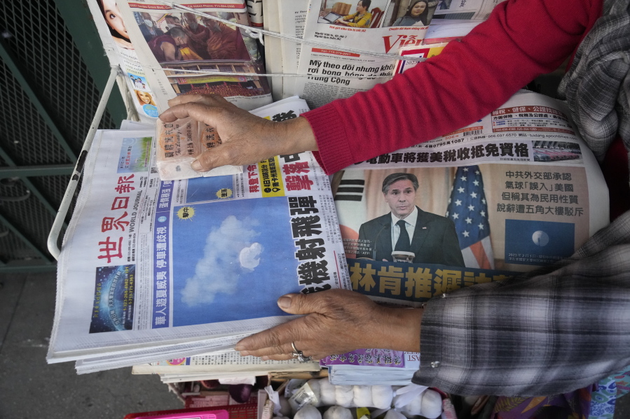 Business owner "Annie" weights down copies of the Chinese Daily News newspaper showcasing pictures of a suspected Chinese spy balloon, in the Chinatown district of Los Angeles Sunday, Feb. 5, 2023. The balloon's presence in the sky above the United States before a military jet shot it down over the Atlantic Ocean with a missile Saturday has further strained U.S.- China ties.
