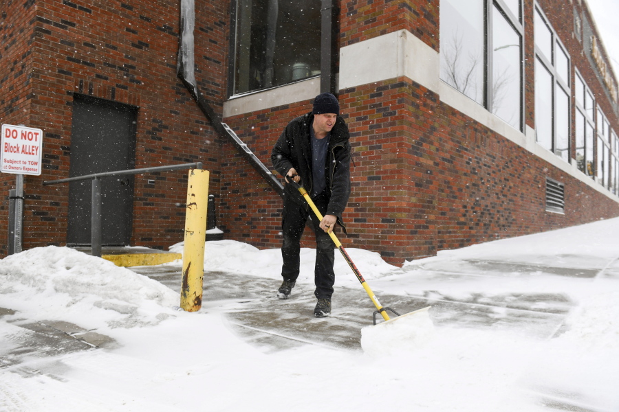 David Smith shovels the sidewalk as the first snow falls ahead of a winter storm on Tuesday, Feb. 21, 2023, in Sioux Falls, S.D.  A wide swath of the Upper Midwest is bracing for a historic winter storm. The system is expected to bury parts of the region in 2 feet of snow, create dangerous blizzard conditions and bring along bitter cold temperatures.