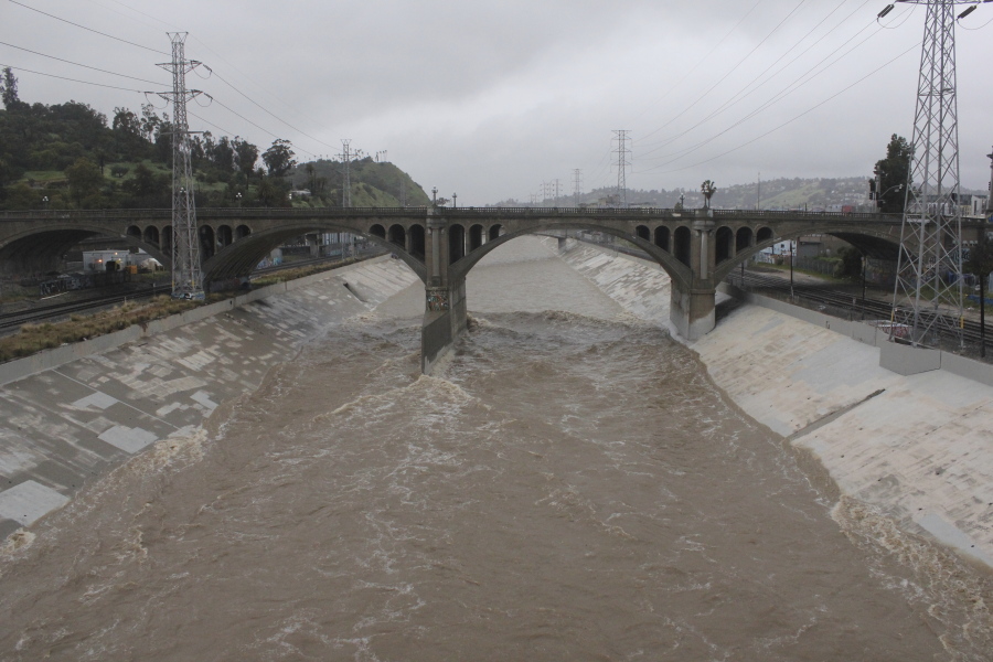 The rain-swollen Los Angeles River flows near downtown Los Angeles on Saturday, Feb. 25, 2023, as a powerful storm pounds Southern California. The National Weather Service said periods of heavy rain and mountain snow would continue before winding down by evening.
