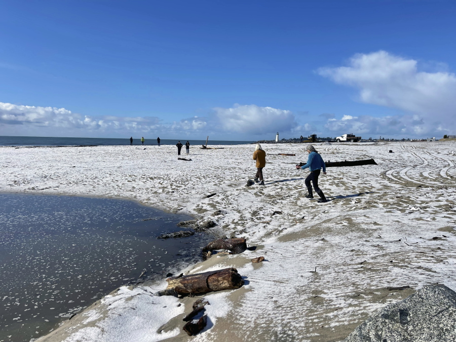 People walk along a snow covered Twin Lakes State Beach in Santa Cruz, Calif., on Thursday, Feb. 23, 2023.