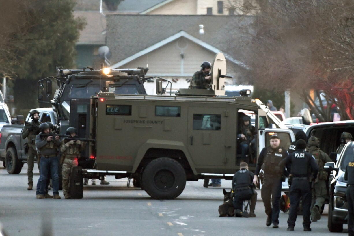 Law enforcement officers aim their weapons at a home during a standoff in Grants Pass, Ore., on Tuesday, Jan. 31, 2023.