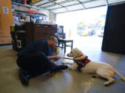 Adam Holwuttle, 35, spends time with Apollo on Jan. 27 in the garage at a Merakey company home in Escondido, Calif. Holwuttle and his housemates have been training Apollo so that he can be placed for adoption. (Nelvin C.