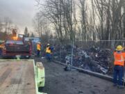 Washington State Department of Transportation workers secure the site of The Swamps homeless encampment in east Vancouver Wednesday afternoon where a fire broke out last week.