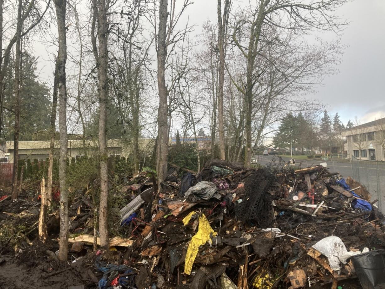 A heap of burned belongings, wood and trash sit by the roadside Wednesday afternoon at the site of The Swamps homeless encampment in east Vancouver.