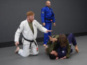 Professional mixed martial arts fighter Ed Herman, left, instructs two students during a class at Fabiano Scherner Brazilian Jiu Jitsu in Hazel Dell. Herman and Don Stoner, center, are owners of the gym, which opened last June.