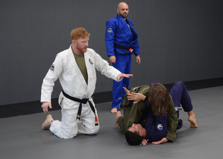Professional mixed martial arts fighter Ed Herman, left, instructs two students during a class at Fabiano Scherner Brazilian Jiu Jitsu in Hazel Dell. Herman and Don Stoner, center, are owners of the gym, which opened last June.