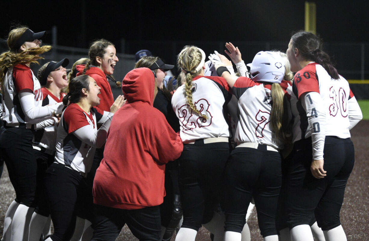 Union players surround teammate Ella Berfanger at home plate after the junior hit a solo home run in the fourth inning against Battle Ground to propel the Titans to a 1-0 victory on Wednesday, March 29, 2023, at Union High School.