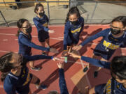 Members of the Montebello High School girls cross country team are careful not to touch hands while wearing masks as they huddle up before a home meet against Bell Gardens High School. Montebello Unified starting to bring students back for athletic events.