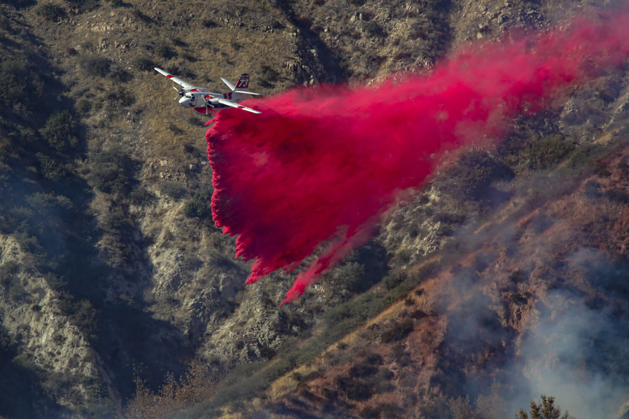 An air tanker drops fire retardant on a slow moving 45 acres brush fire above Glen Helen Parkway on Saturday, Dec. 26, 2020, in Lytle Creek, California.