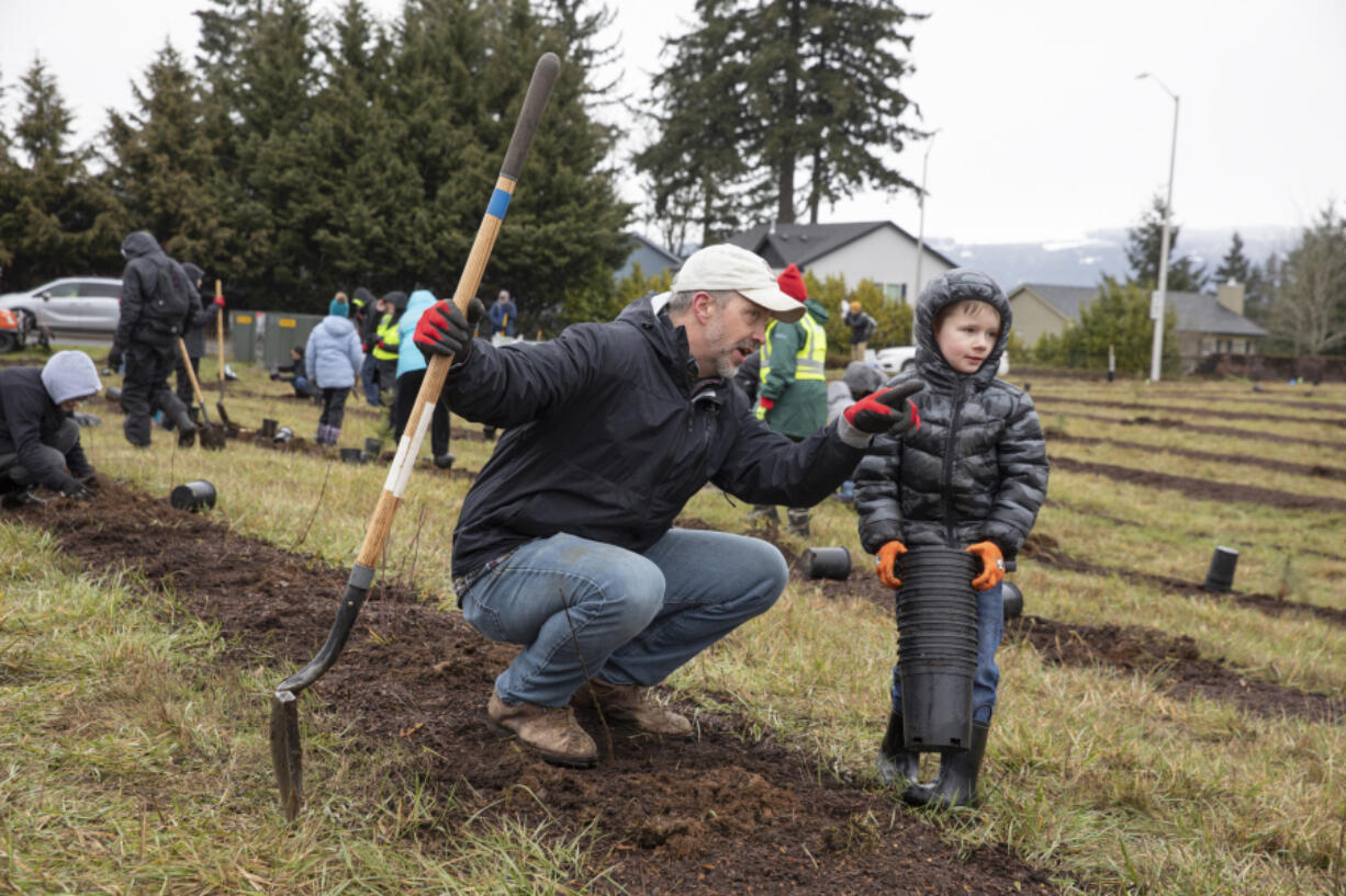 Pat Henderson, left, talks to his nephew, Elijah Osborn, 8, during a planting event hosted by the Watershed Alliance of Southwest Washington. More than a dozen of Henderson's family members joined to celebrate his 46th birthday.