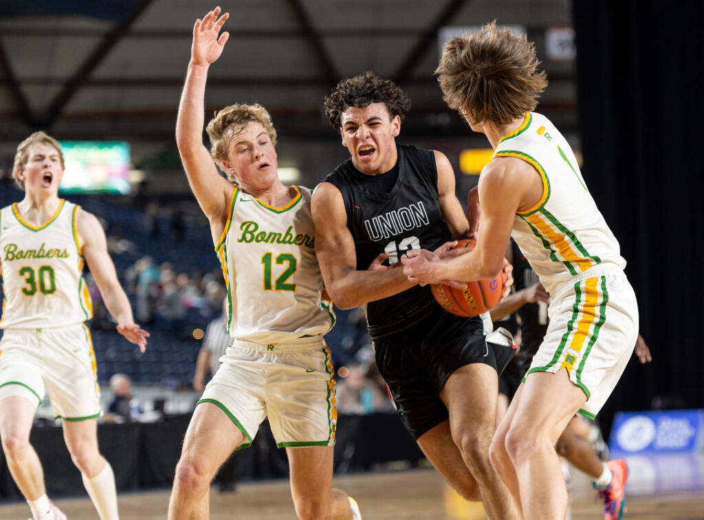 Union senior forward Yanni Fassilis drives against Richland junior guard Josh Woodard and Richland junior forward Lucas Westerfield during a Class 4A State boys basketball game on Wednesday, March 1, 2023, at the Tacoma Dome.