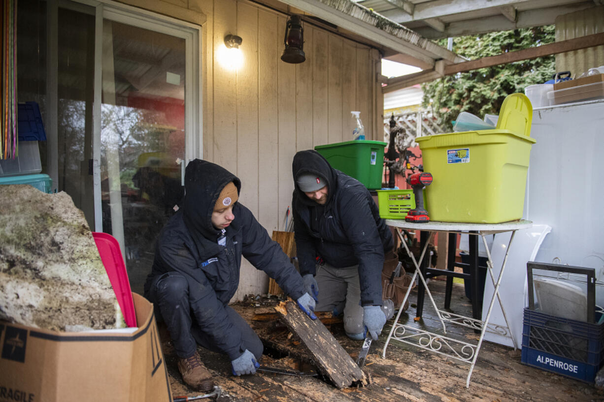 Colten Cramer of TMG Maintenance Services NW, left, works with colleague Jordan Harrington as they remove damaged wood from Linnea and Loren Kurtz's back porch earlier this month.