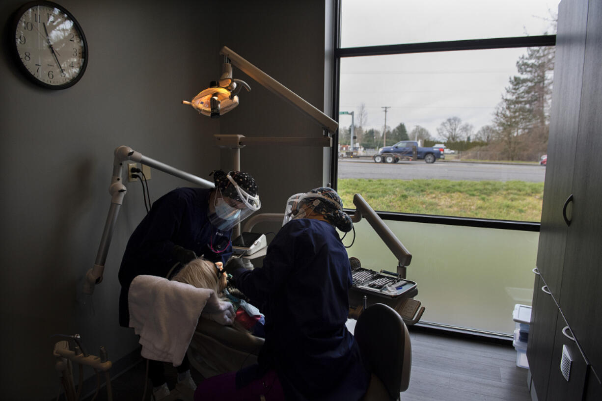 Clark College dental hygiene student Sophia Azizi, from left, works with patient Andrea Dyroff while joined by fellow student Ellie Chapman at Battle Ground HealthCare. Battle Ground HealthCare has partnered with the Clark College dental hygiene program to offer a series of five free teeth-cleaning clinics to the community.
