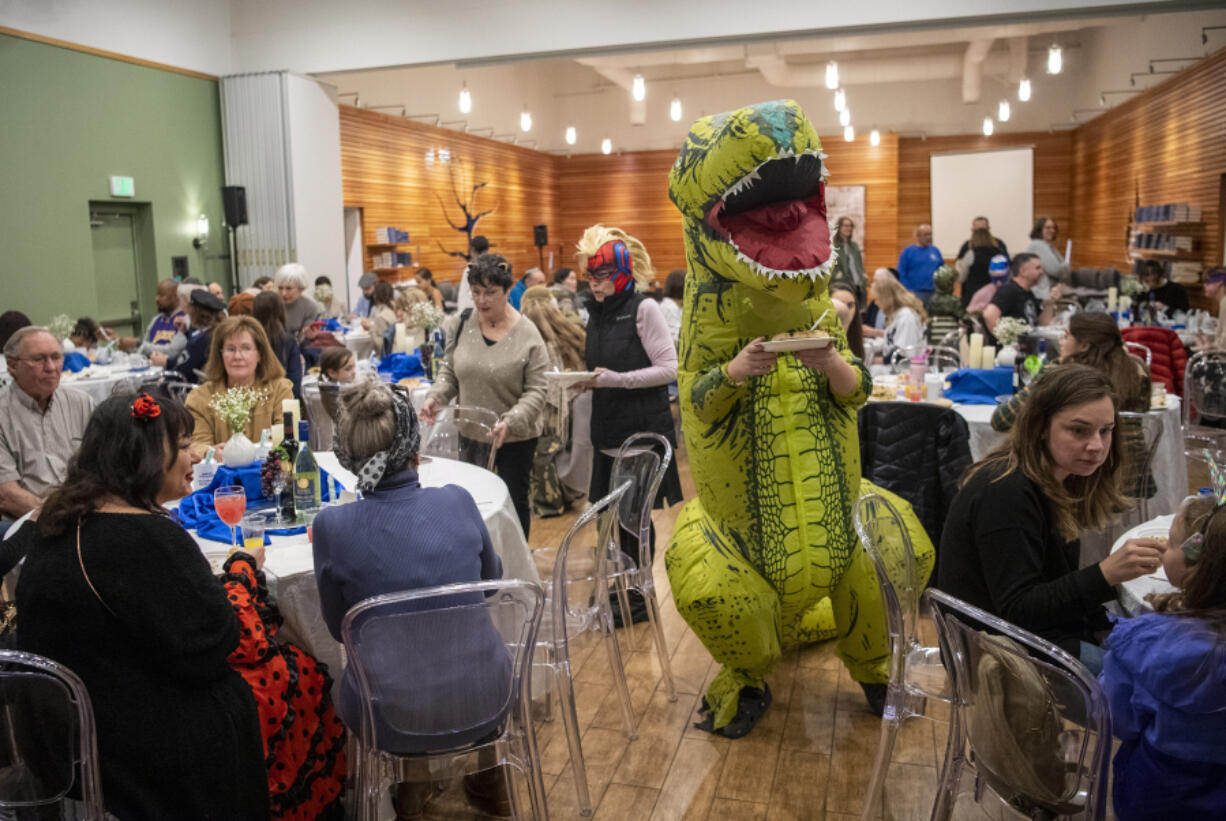 Ari Mittelman, 12, wearing an inflatable T-Rex costume, looks for a place to eat during Tuesday's Purim celebration at the Chabad Jewish Center in Vancouver.