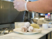 Donuts receive a sprinkle of powdered sugar before leaving the kitchen at Cecilia.