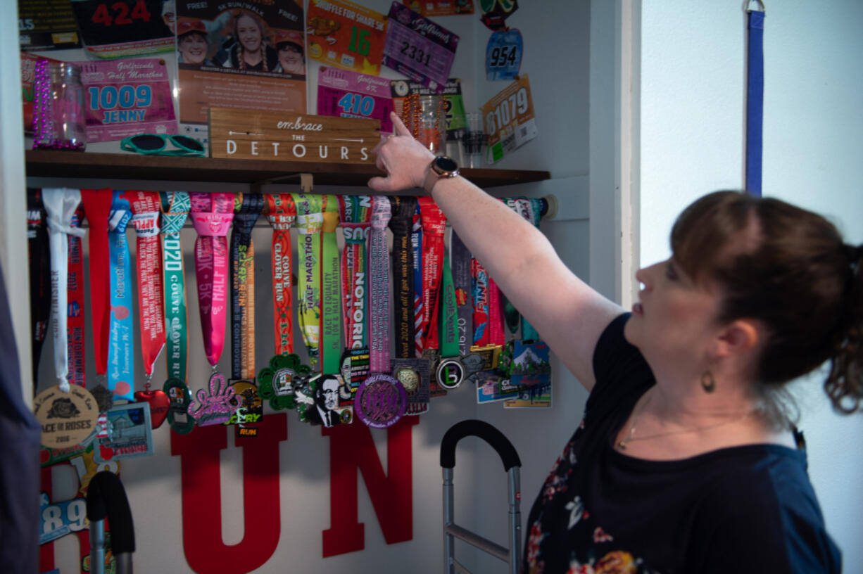 Jenny Bevard shows off her collection of marathon and half-marathon medals in her Vancouver home. Before getting long COVID, she was an avid runner. Now, even a walk inside from the car can leave her short of breath.
