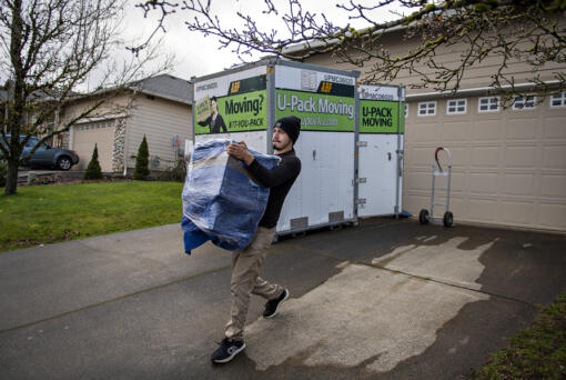 Xavier Lopez of Miracle Man Movers carries a piece of furniture for a customer moving from Washougal to Vancouver. The company moves people all over the region but has helped more clients make the journey from Oregon to Washington than the other direction.