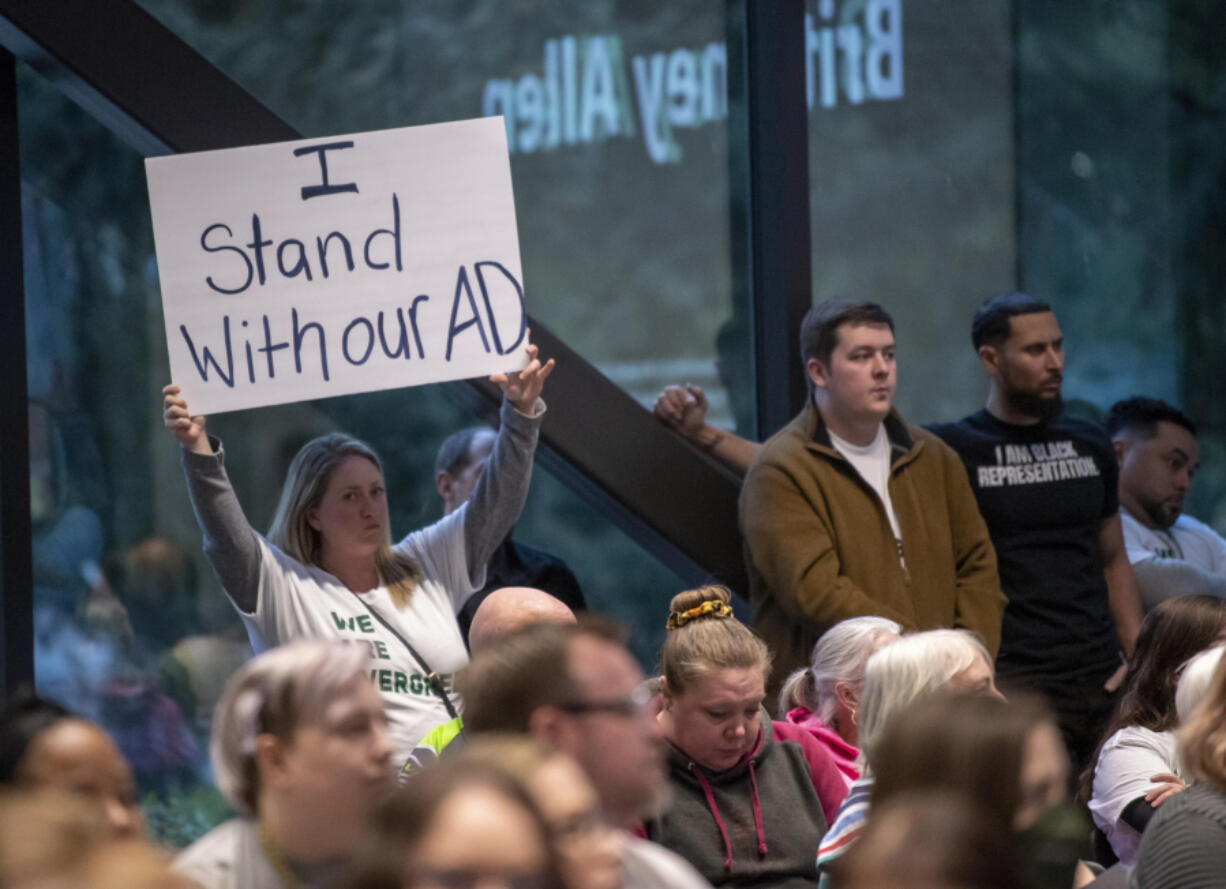 An audience members holds up a sign in support of athletic directors Tuesday during an Evergreen Public Schools meeting at Evergreen Public Schools headquarters.