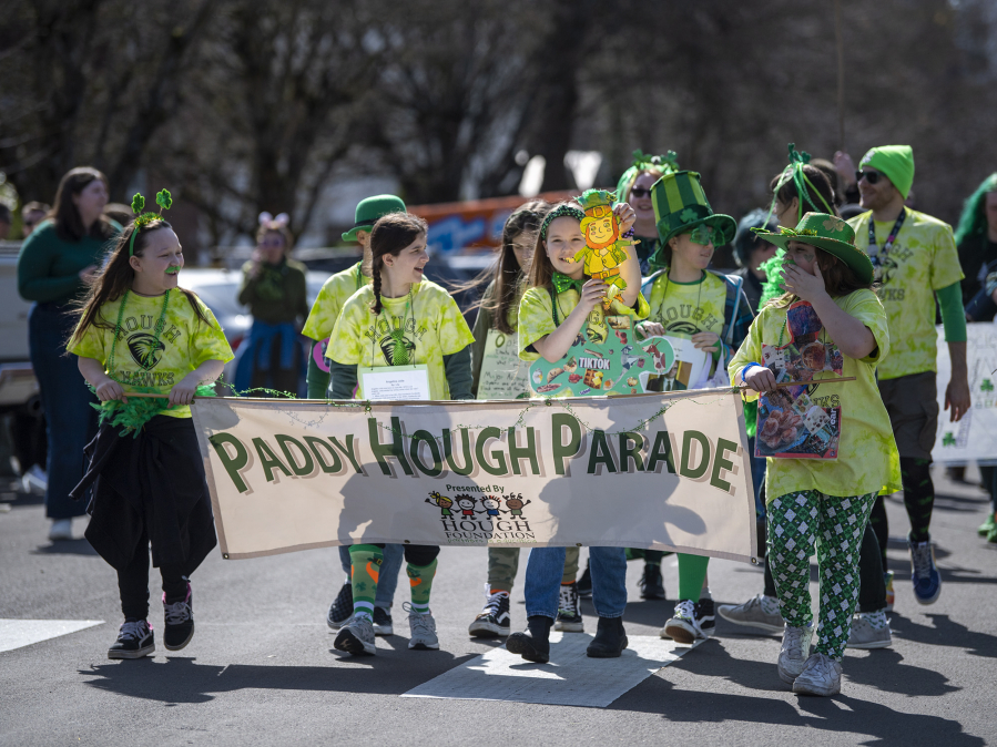 Hough Elementary School students march and hold a banner Friday during the Paddy Hough Parade in Vancouver in 2023.