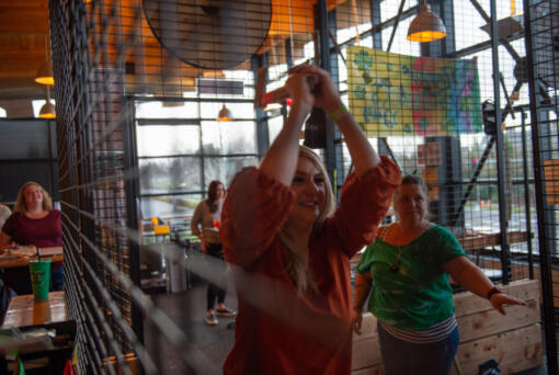 Bethany Seegert of Vancouver, left, gets pointers from ax matron Darbi Johnson of Portland at Celtic Axe Throwers' lanes inside Hopworks Urban Brewery in Vancouver. (James Rexroad for The Columbian)
