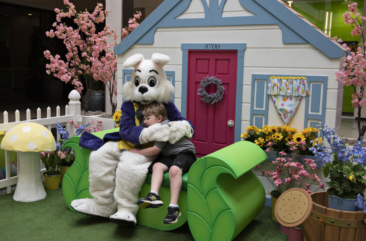 The Easter Bunny shares some love with Troy Allen Raye, 6, of Vancouver as they pose for some fun photos Monday afternoon at Vancouver Mall. At top, the Easter Bunny's energetic demeanor attracted children who ran down the hallway for a chance to give the bunny a high-five.
