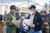Vietnam veteran Patrick Locke, left, hands out commemorative pins and papers to other veterans before the Witness Tree dedication at Clark College.