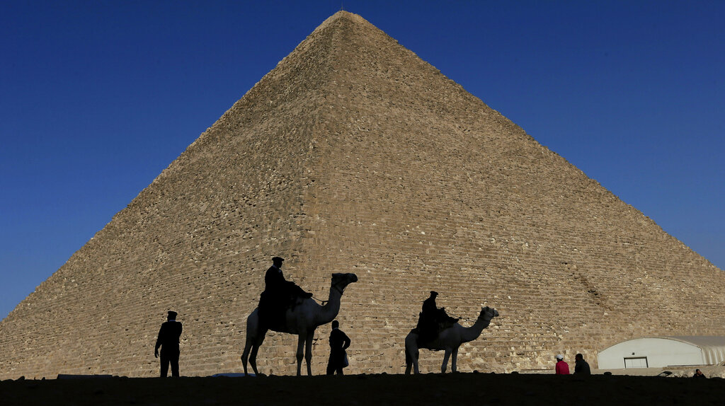 FILE - Policemen are silhouetted against the Great Pyramid in Giza, Egypt, Dec 12, 2012. Egypt unveiled on Thursday, March 2, 2023, the discovery of a 9-meter-long chamber inside the Great Pyramid of Giza, the first to be found on the structure’s north side.