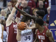 Washington center Braxton Meah, center, attempts to drive against Washington State forward Andrej Jakimovski, left, guard TJ Bamba, right, and forward Mouhamed Gueye during the second half of an NCAA college basketball game Thursday, March 2, 2023, in Seattle.