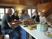 Doug Whitney, center, eats breakfast with his family in Manson, Wash., on Nov. 5, 2022. Whitney inherited the same gene mutation that gave Alzheimer's disease to his mother, brother and generations of other relatives by the unusually young age of 50. Doug is a healthy 73, his mind still sharp. Somehow, he escaped his genetic fate.