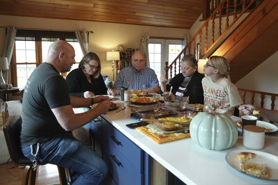 Doug Whitney, center, eats breakfast with his family in Manson, Wash., on Nov. 5, 2022. Whitney inherited the same gene mutation that gave Alzheimer's disease to his mother, brother and generations of other relatives by the unusually young age of 50. Doug is a healthy 73, his mind still sharp. Somehow, he escaped his genetic fate.