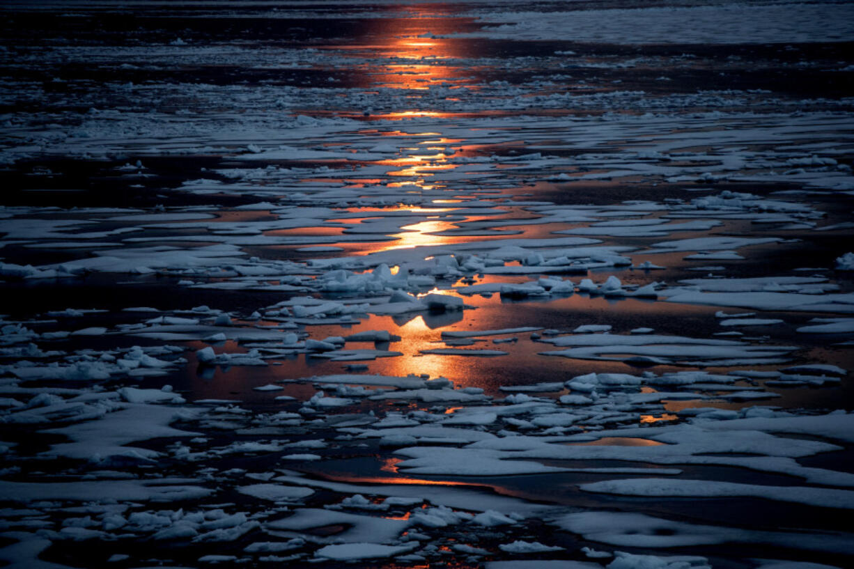 FILE - The midnight sun shines across sea ice along the Northwest Passage in the Canadian Arctic Archipelago, July 23, 2017. A new study Wednesday, March 15, 2023, says the thickness of sea ice dropped sharply in two sudden events about 15 years ago.