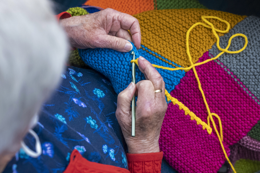 In this photo provided by Edward Boches, a volunteer adds a border to a blanket, Jan. 8, 2023 in Brookline, Mass. The Welcome Blankets will be donated to agencies helping immigrants who recently arrived in the United States.