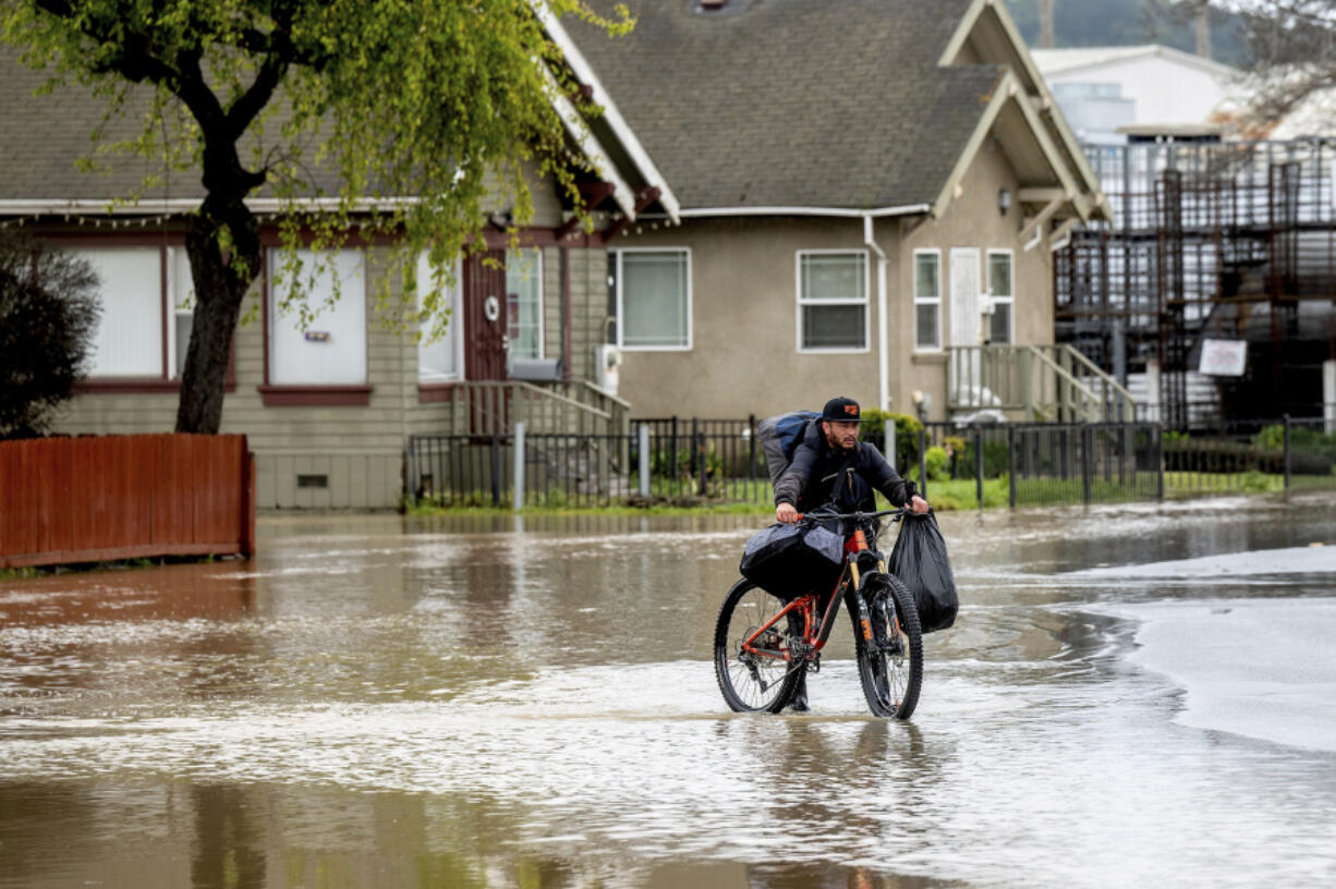 Erik Narez walks through floodwaters while leaving his home in the community of Pajaro in Monterey County, Calif., on Monday, March 13, 2023.