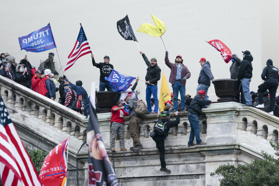 FILE - Rioters wave flags on the West Front of the U.S. Capitol in Washington on Jan. 6, 2021. Federal prosecutors are employing an unusual strategy to prove leaders of the far-right Proud Boys extremist group orchestrated a violent plot to keep President Joe Biden out of the White House, even though some of the defendants didn't carry out the violence themselves.