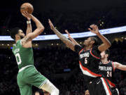 Boston Celtics forward Jayson Tatum, left, prepares to shoot a basket over Portland Trail Blazers forwards Cam Reddish, center, and Drew Eubanks, right, during the first half of an NBA basketball game in Portland, Ore., Friday, March 17, 2023.