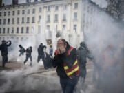 Protesters run amid the tear gas during a demonstration Thursday in Lyon, central France.