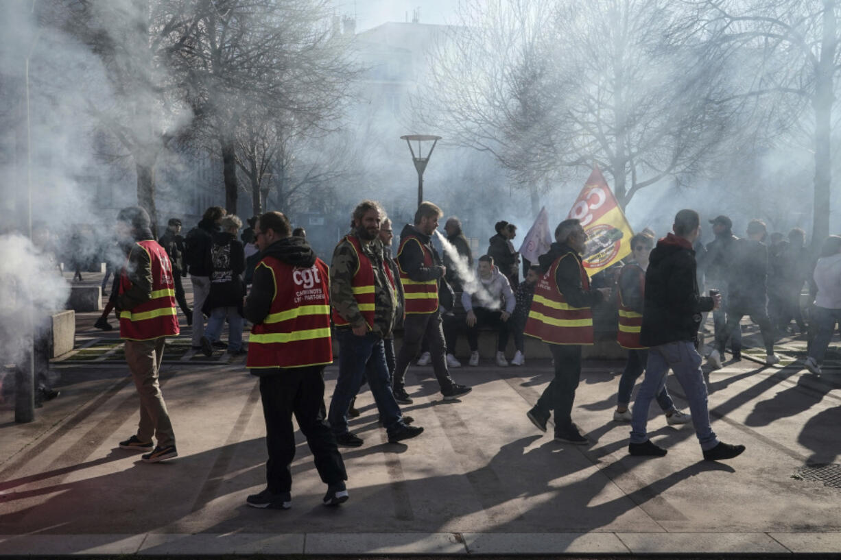Unions members use flares during a demonstration in Lyon, central France, Wednesday, March 15, 2023. Opponents of French President Emmanuel Macron's pension plan are staging a new round of strikes and protests as a joint committee of senators and lower-house lawmakers examines the contested bill.