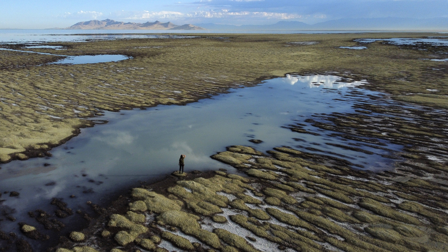 FILE - State of Utah Department of Natural Resources park ranger Angelic Lemmon walks across reef-like structures called microbialites, exposed by receding waters at the Great Salt Lake on Wednesday, Sept. 28, 2022, near Salt Lake City. Amid rising panic about the future of Utah's Great Salt Lake, The Church of Jesus Christ of Latter-day Saints is putting newfound emphasis on environmental stewardship. A high-ranking church official spoke to scientists and politicians at the University of Utah on Friday, March 17, 2023, about the church's recent move to donate 20,000 acre-feet of water to help maintain the elevation of the Great Salt Lake and commitment to re-landscaping its temples and meetinghouses known for their neatly manicured grass.