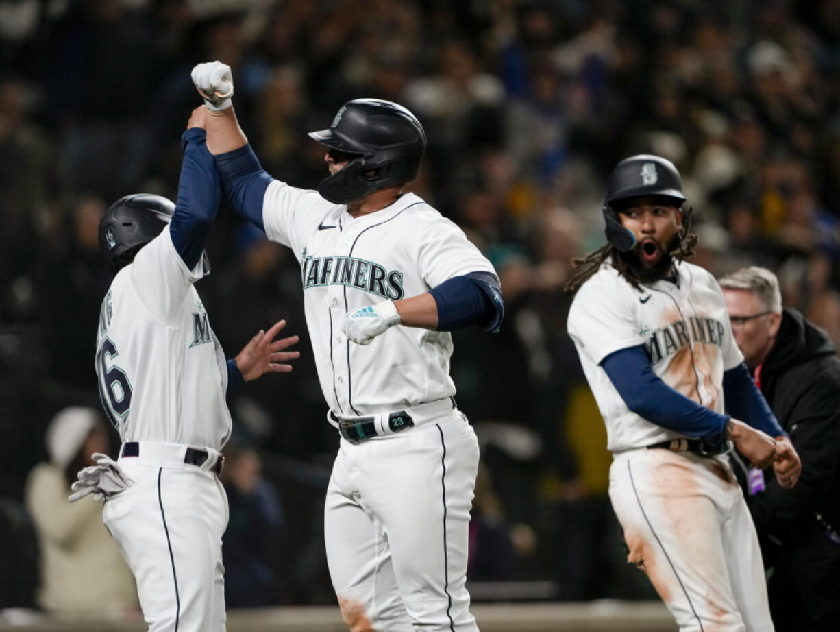 Seattle Mariners' Ty France, center, celebrates his three-run home run against the Cleveland Guardians with Kolten Wong, left, and J.P. Crawford, right, during the eighth inning of an opening day baseball game Thursday, March 30, 2023, in Seattle.