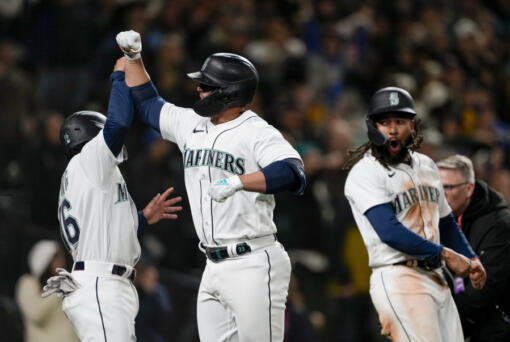 Seattle Mariners' Ty France, center, celebrates his three-run home run against the Cleveland Guardians with Kolten Wong, left, and J.P. Crawford, right, during the eighth inning of an opening day baseball game Thursday, March 30, 2023, in Seattle.