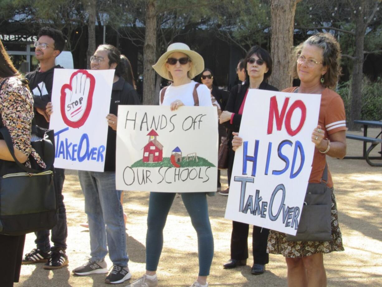 People hold up signs at a news conference on Friday, March 3, 2023, in Houston while protesting the proposed takeover of the city's school district by the Texas Education Agency. Local and federal officials say state leaders are preparing to take over the Houston Independent School District over allegations of misconduct by district board members and the yearslong failing performance of one campus. ( Juan A.