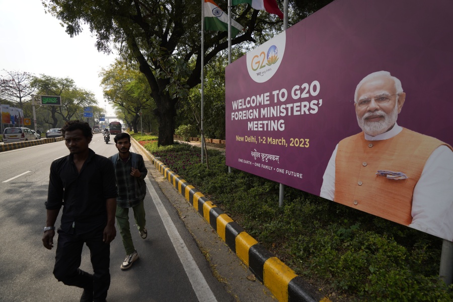 Commuters walk past a banner with Indian Prime Minister's Narendra Modi photograph welcoming delegates of G20 foreign ministers meeting, in New Delhi, India, Wednesday, March 1, 2023. Fractured East-West relations over Russia's war in Ukraine and increasing concerns about China's global aspirations are set to dominate what is expected to be a highly contentious meeting of foreign ministers from the world's largest industrialized and developing nations this week in India.