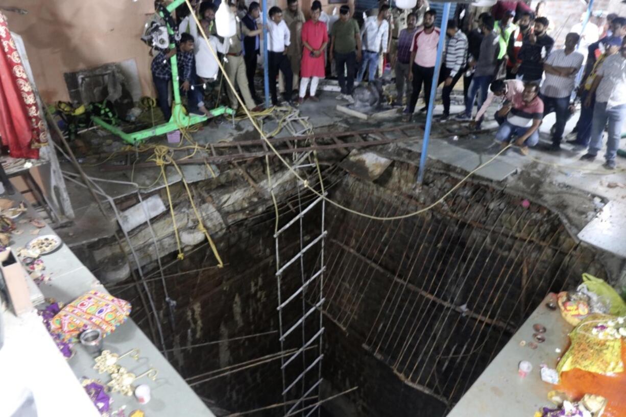 People stand around a structure built over an old temple well that collapsed Thursday as a large crowd of devotees gathered for the Ram Navami Hindu festival in Indore, India, Thursday, March 30, 2023. Up to 35 people fell into the well in the temple complex when the structure collapsed and were covered by falling debris, police Commissioner Makrand Deoskar said. At least eight were killed.