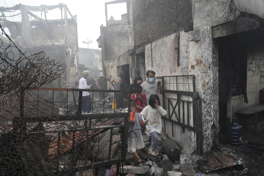 Residents walk though the rubble at a neighborhood affected by a fuel depot fire in Jakarta, Indonesia, Saturday, March 4, 2023. A large fire broke out at the fuel storage depot in Indonesia's capital Friday, killing multiple people, injuring dozens of others and forcing the evacuation of thousands of nearby residents after spreading to their neighborhood, officials said.