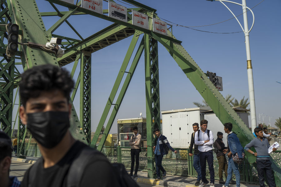 Youths wait for a ride on the bridge crossing the Euphrates River in Fallujah, Iraq, Thursday, March 2, 2023. In 2004, four armed contractors working for the private military contractor Blackwater were killed and their bodies hung from the bridge.