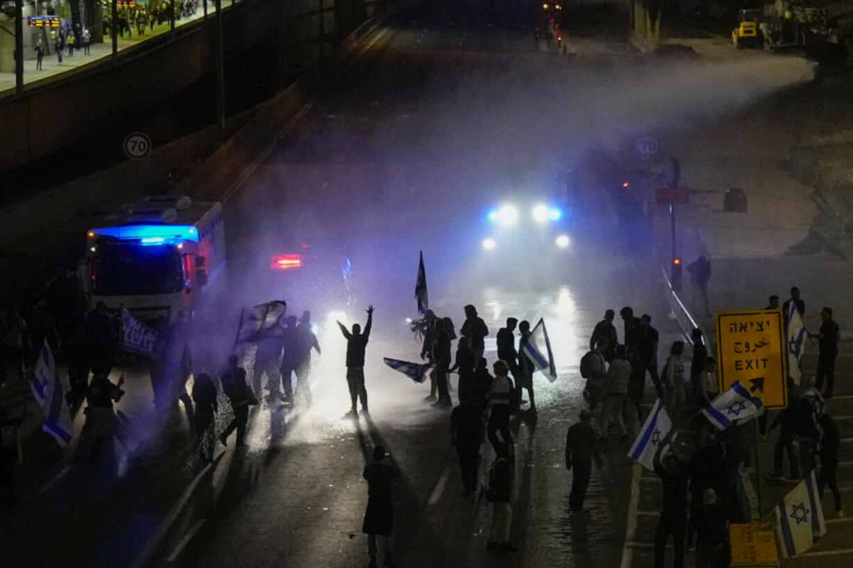 Israeli police use a water cannon to disperse Israelis blocking the freeway during a protest against plans by Prime Minister Benjamin Netanyahu's government to overhaul the judicial system in Tel Aviv, Israel, Saturday, March 25, 2023.