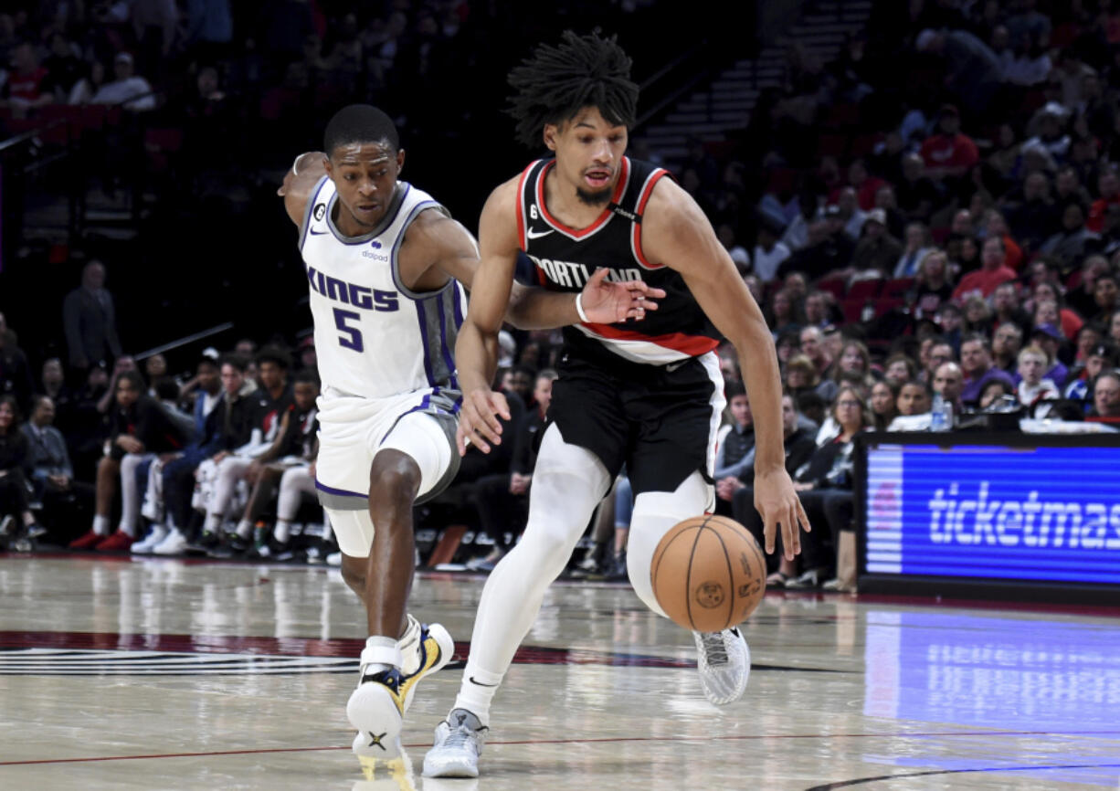 Sacramento Kings guard De'Aaron Fox, left, reaches for the ball as Portland Trail Blazers guard Shaedon Sharpe drives during the second half of an NBA basketball game in Portland, Ore., Friday, March 31, 2023.